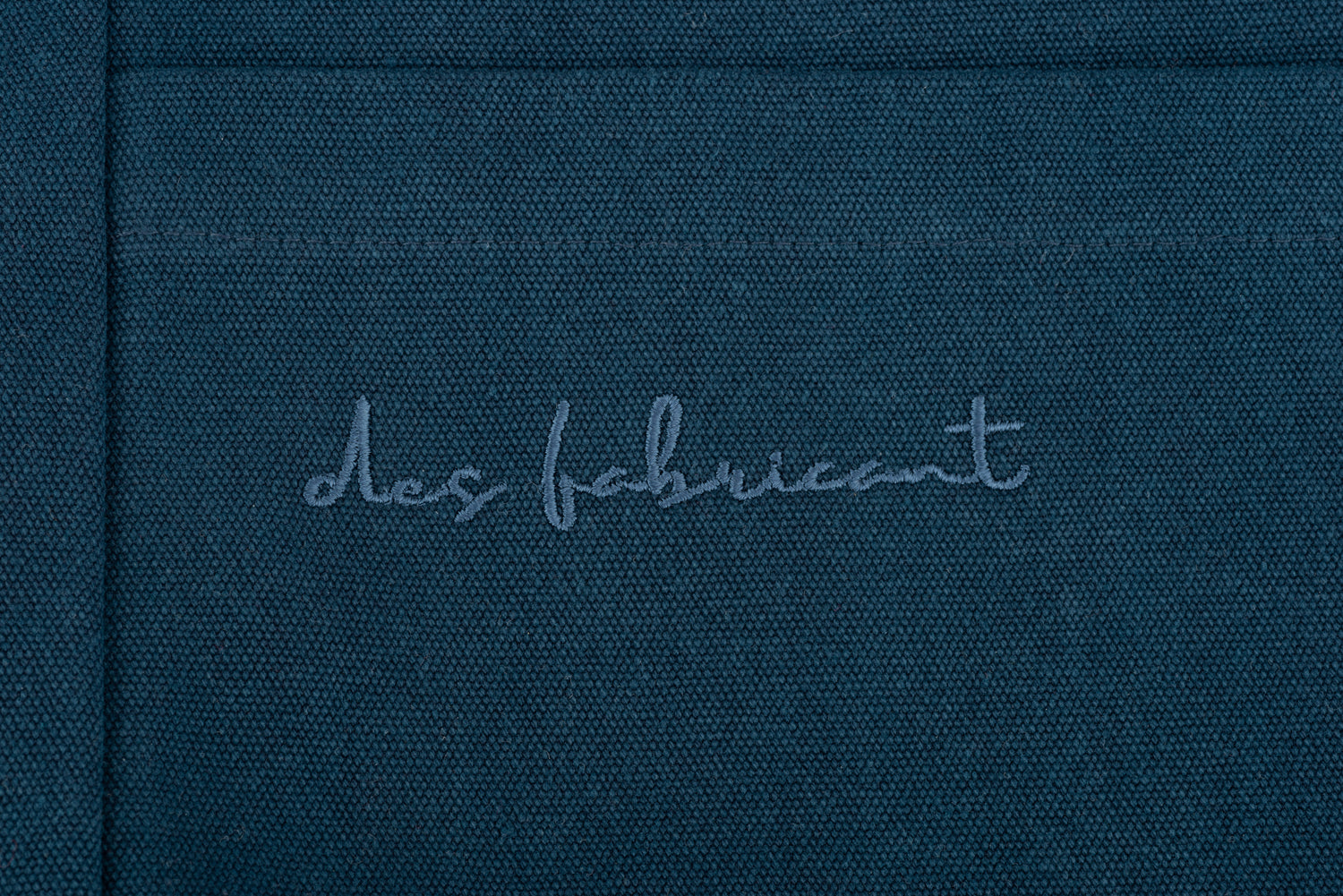 Embossed Des Fabricant logo detail on premium dark blue cotton fabric -subtle, refined branding.